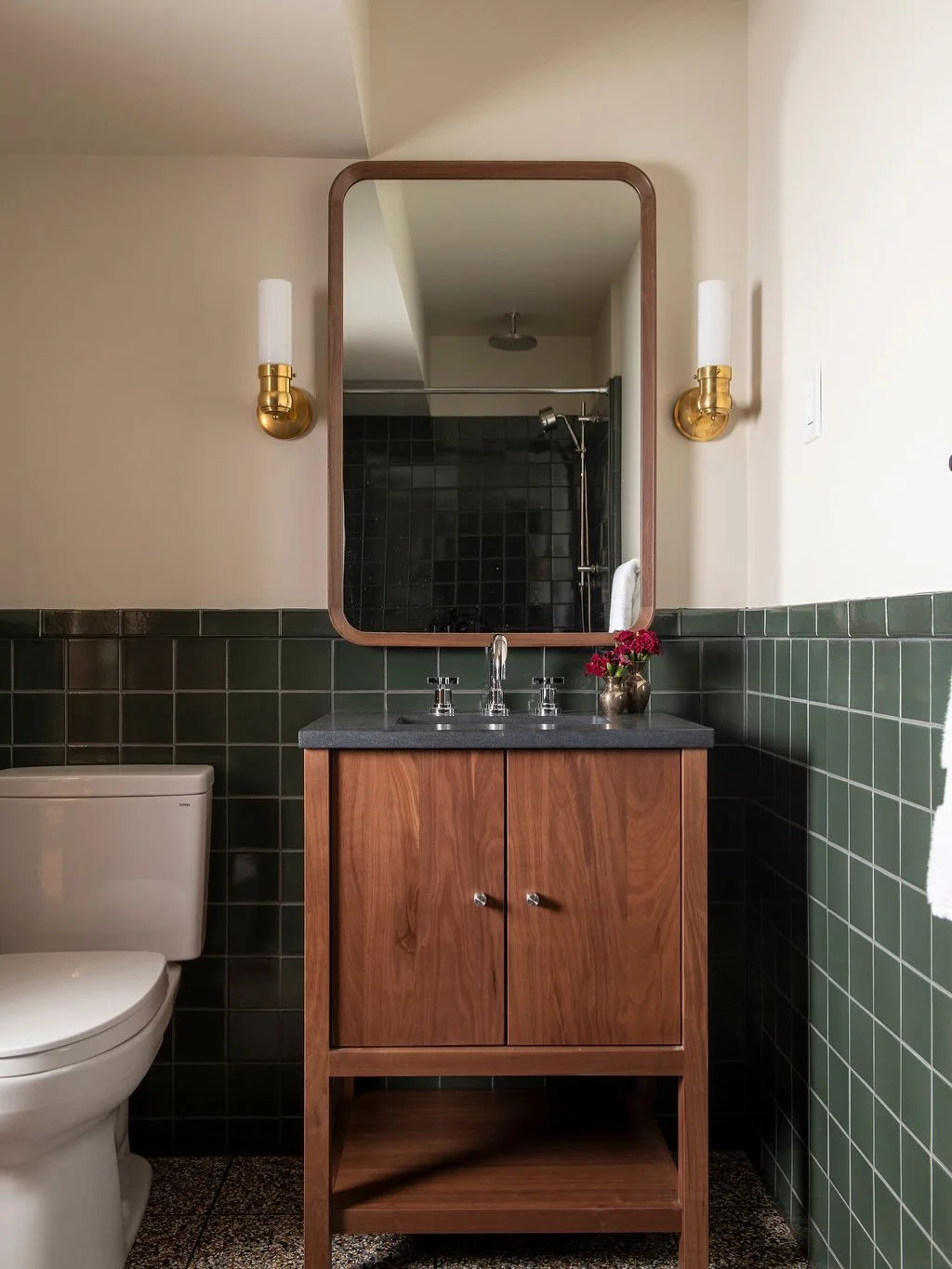 The lower level bathroom was redesigned to maximize both luxury and functionality within the existing footprint.  Beautiful tile installations, including terrazzo flooring, bring texture and personality to the spaces, while walnut storage solutions p