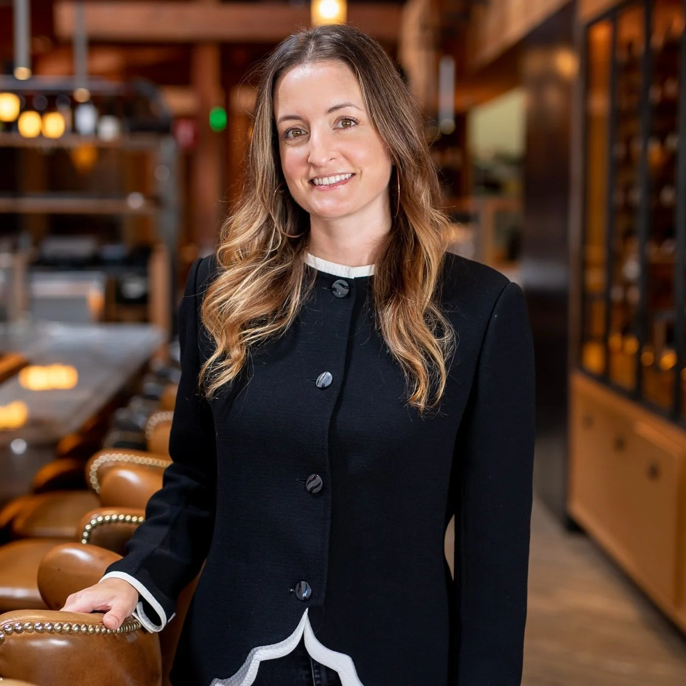 Alexandra is smiling in the restaurant with her hand resting on a bar stool