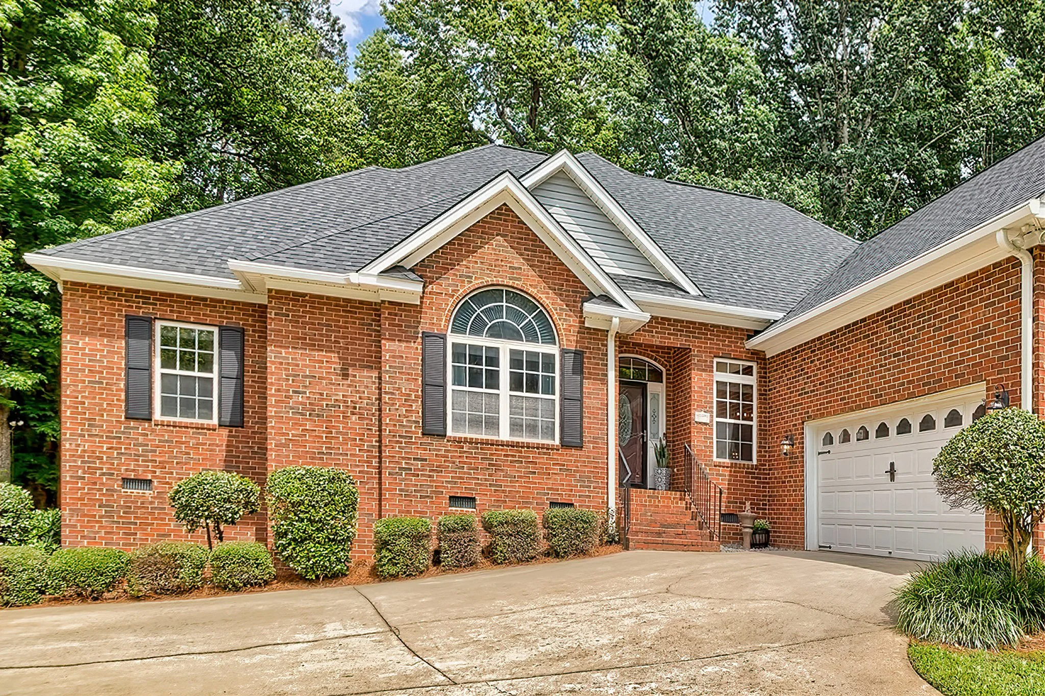 Traditional brick ranch home exterior with garage and mature trees in The Landings, Lexington, SC