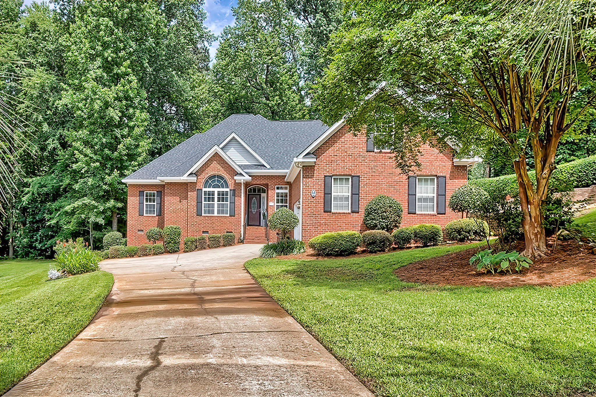Brick ranch home exterior with arched window and landscaped driveway in The Landings, Lexington, SC