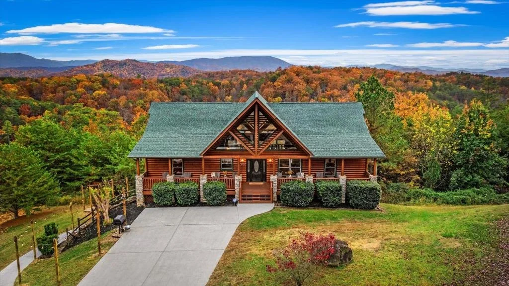log cabin with fall foliage and mountains in background