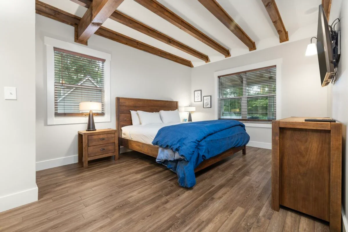 King bed in a room with white walls and exposed wooden beams