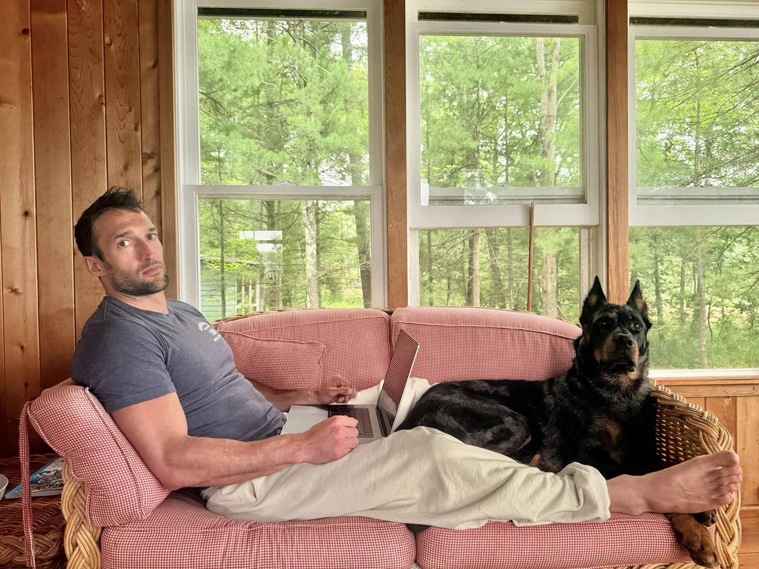 A Beauceron relaxing beside its owner at home.