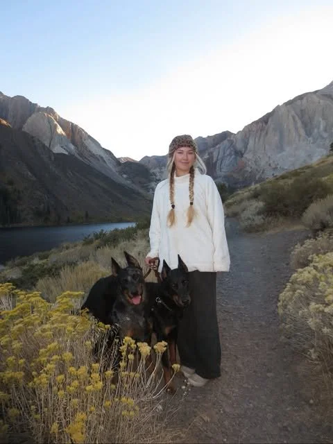 McKenzie with her two Beaucerons beside a mountain lake.