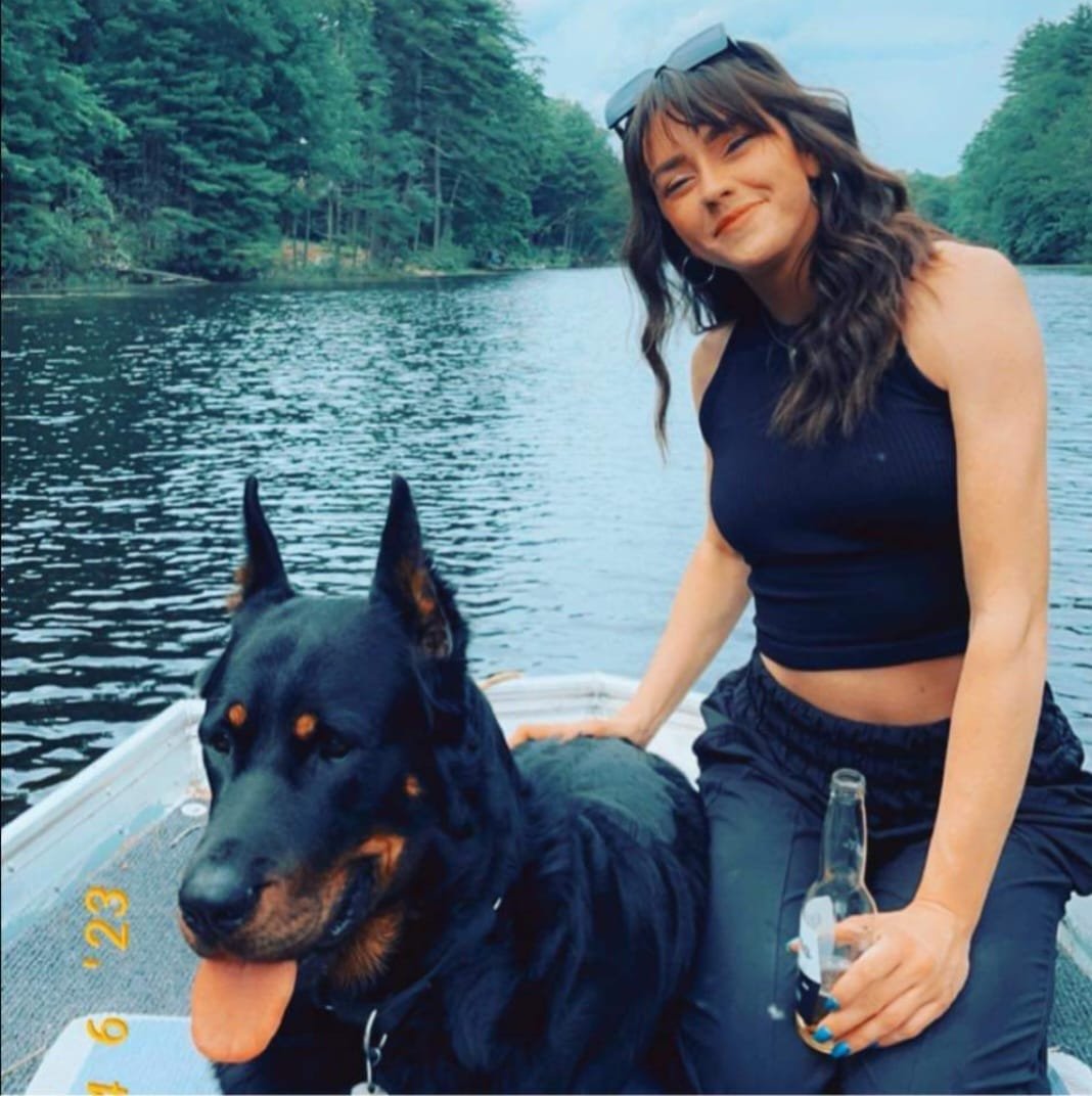 A woman and Beauceron enjoy time together aboard a boat.
