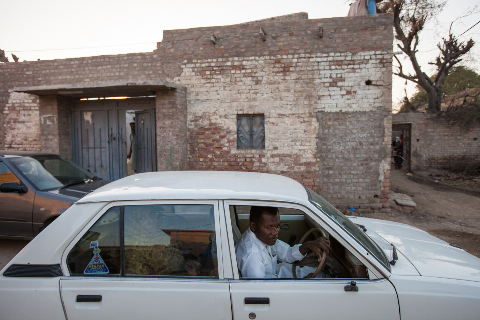 A Sheedi man drives a car through his village outside of Hyderabad. Hyderabad, Pakistan.