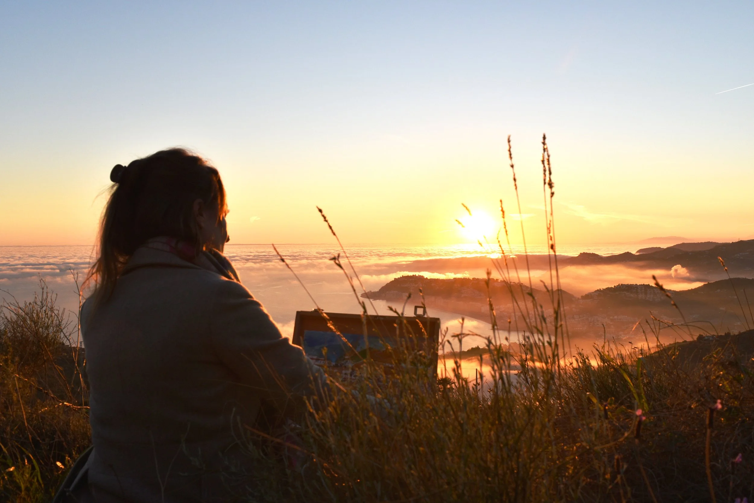 Annabel is painting atop of a mountain in La Alpujarra, Spain, during sunset.