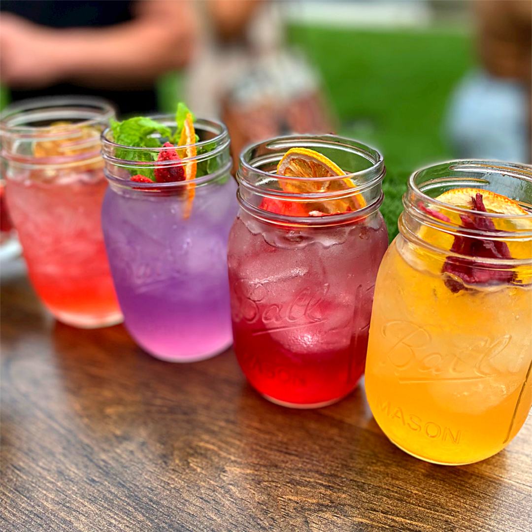 handlebar services | Assorted colorful handcrafted cocktails arranged together, showcasing a variety of garnishes and vibrant hues