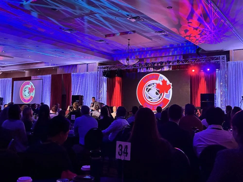 Audience attending the Calgary Police Service Cybersecurity Summit featuring stage presentations and cybersecurity discussions on regional cyber threats, critical infrastructure protection, and digital resilience.