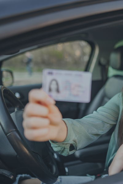 Person holding a driver’s licence inside a vehicle.