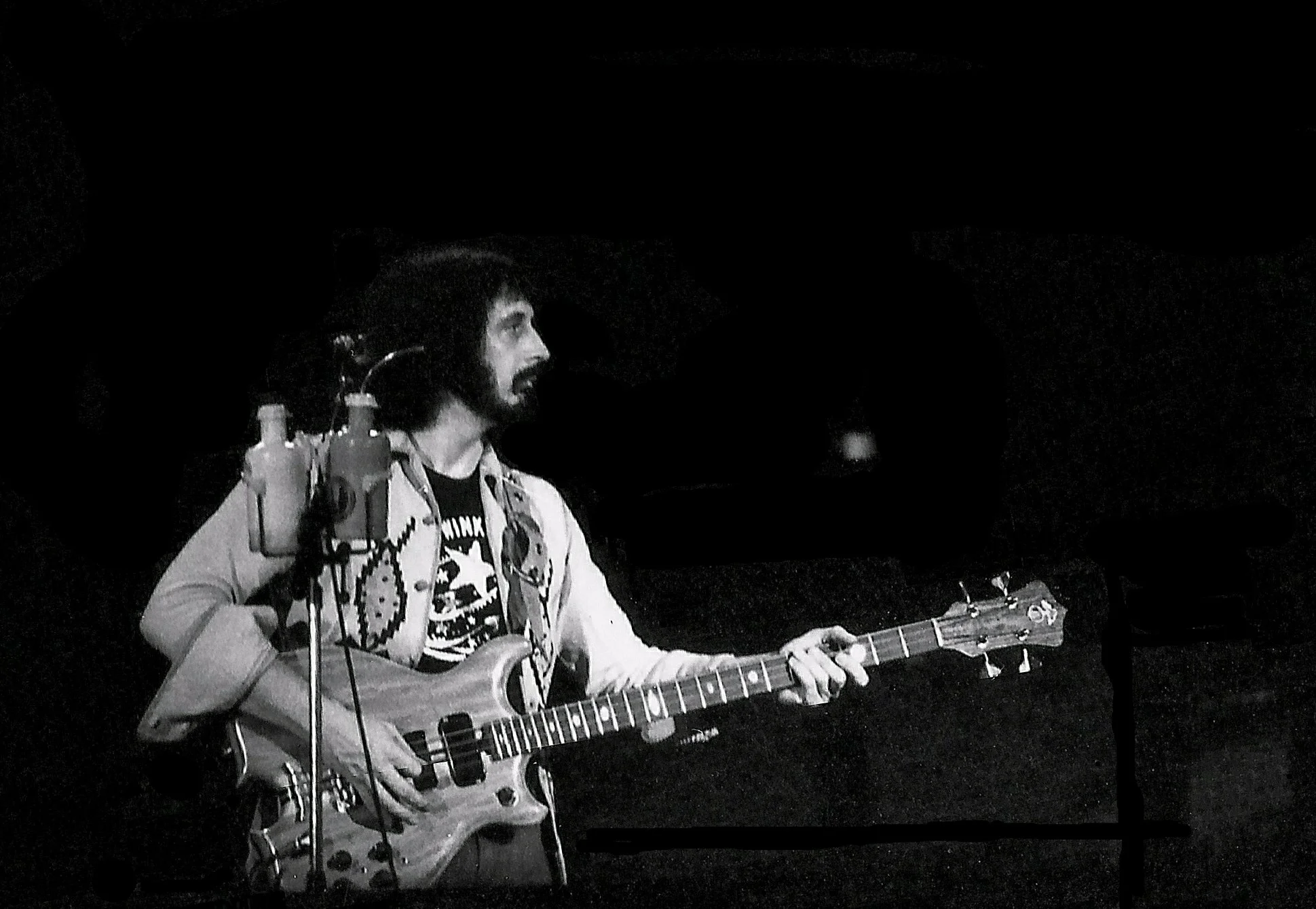 A black and white image of John Entwistle playing the bass guitar, 1976