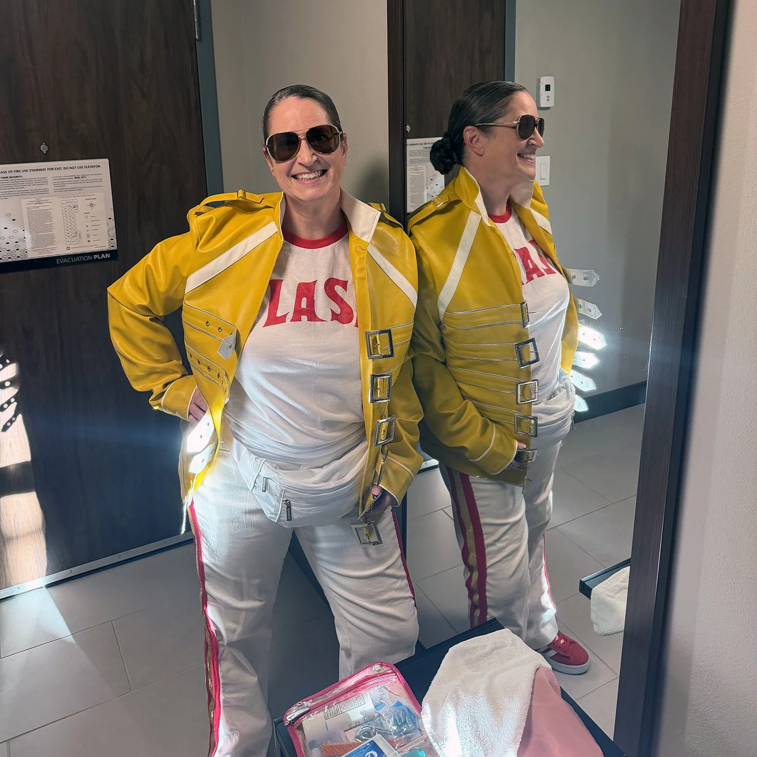 Maria Morris standing by a hotel room mirror dressed as Freddie Mercury