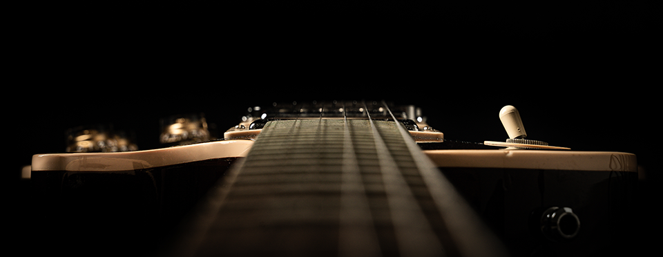 an extreme close-up photograph of an electric guitar looking down the neck