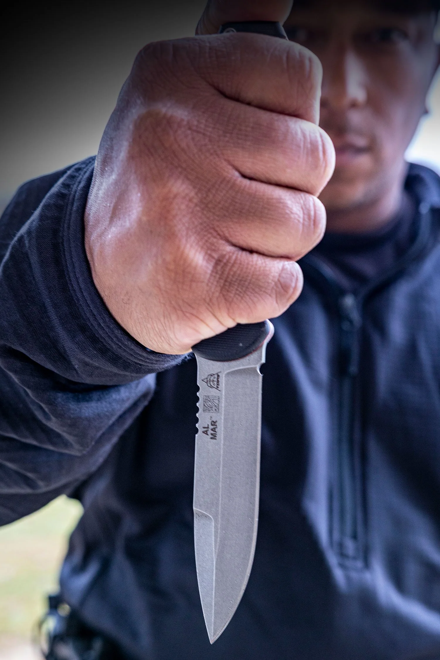 The Made In The USA SERE® Operator Knife being held by a user showing the Tops Knives and Al Mar Knives Logos.