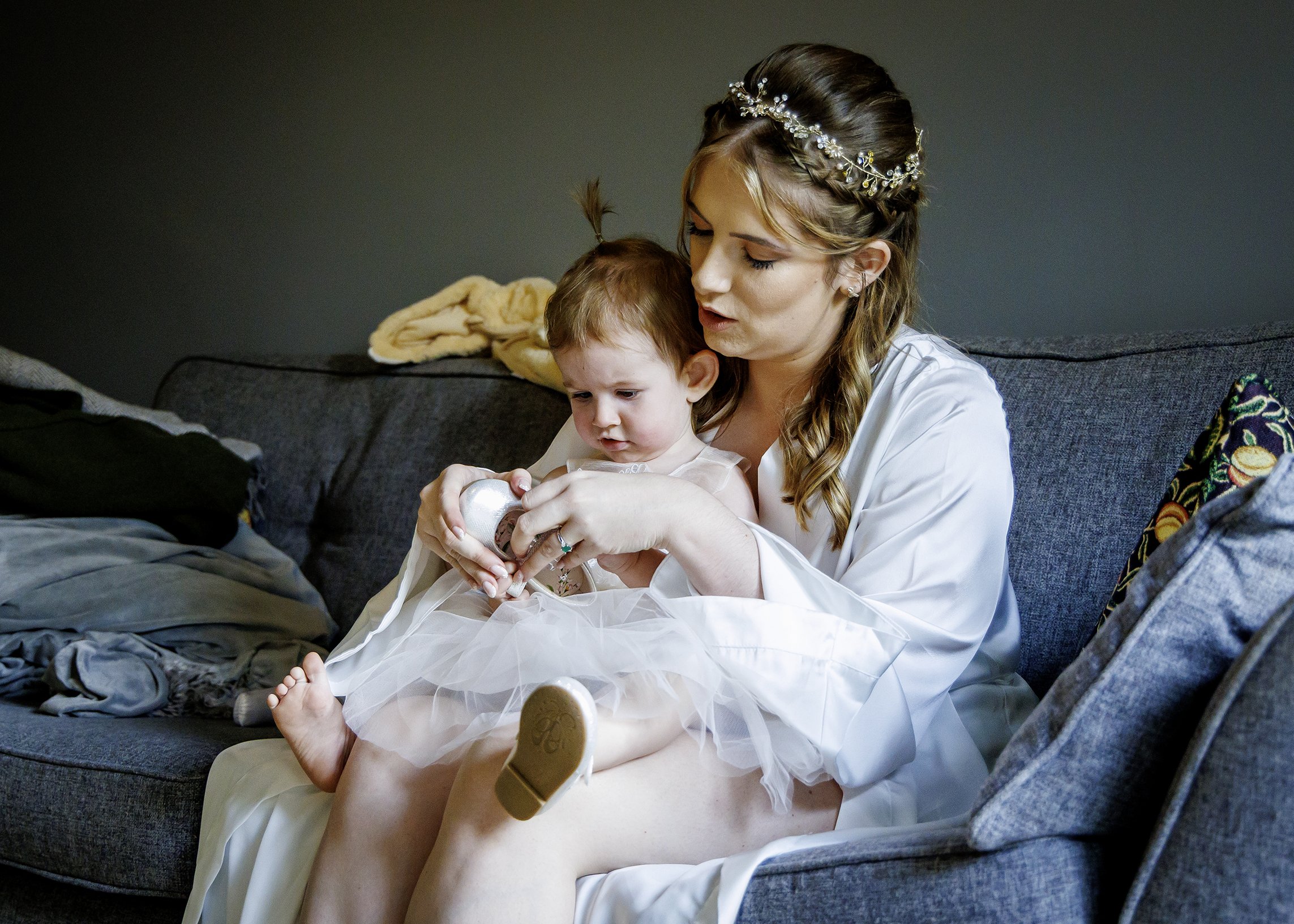 The bride helps her child put in shoes in this cute candid wedding photograph taken before the ceremony