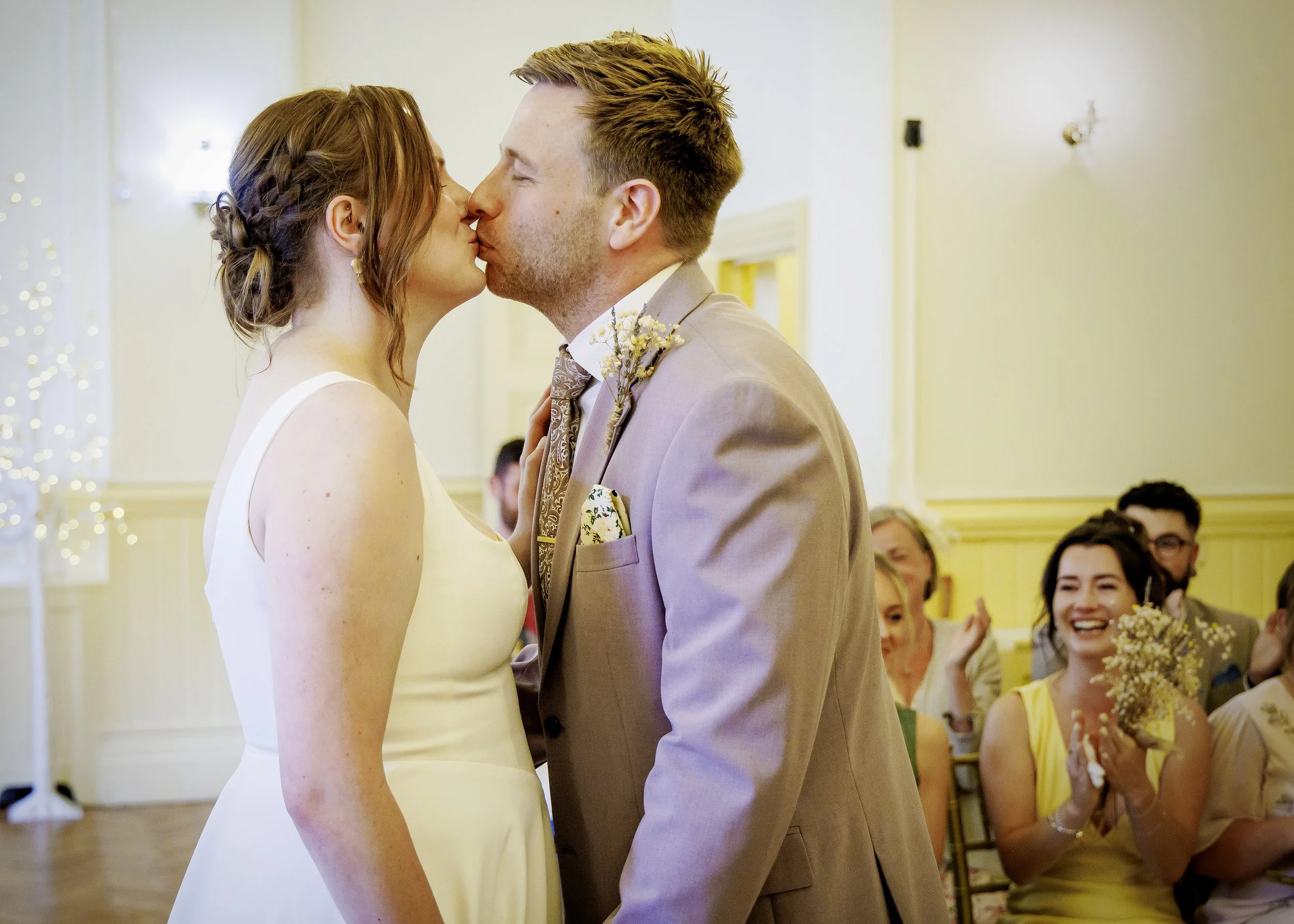 The bride and groom kiss in the light-filled Regency Room, Brighton East Sussex