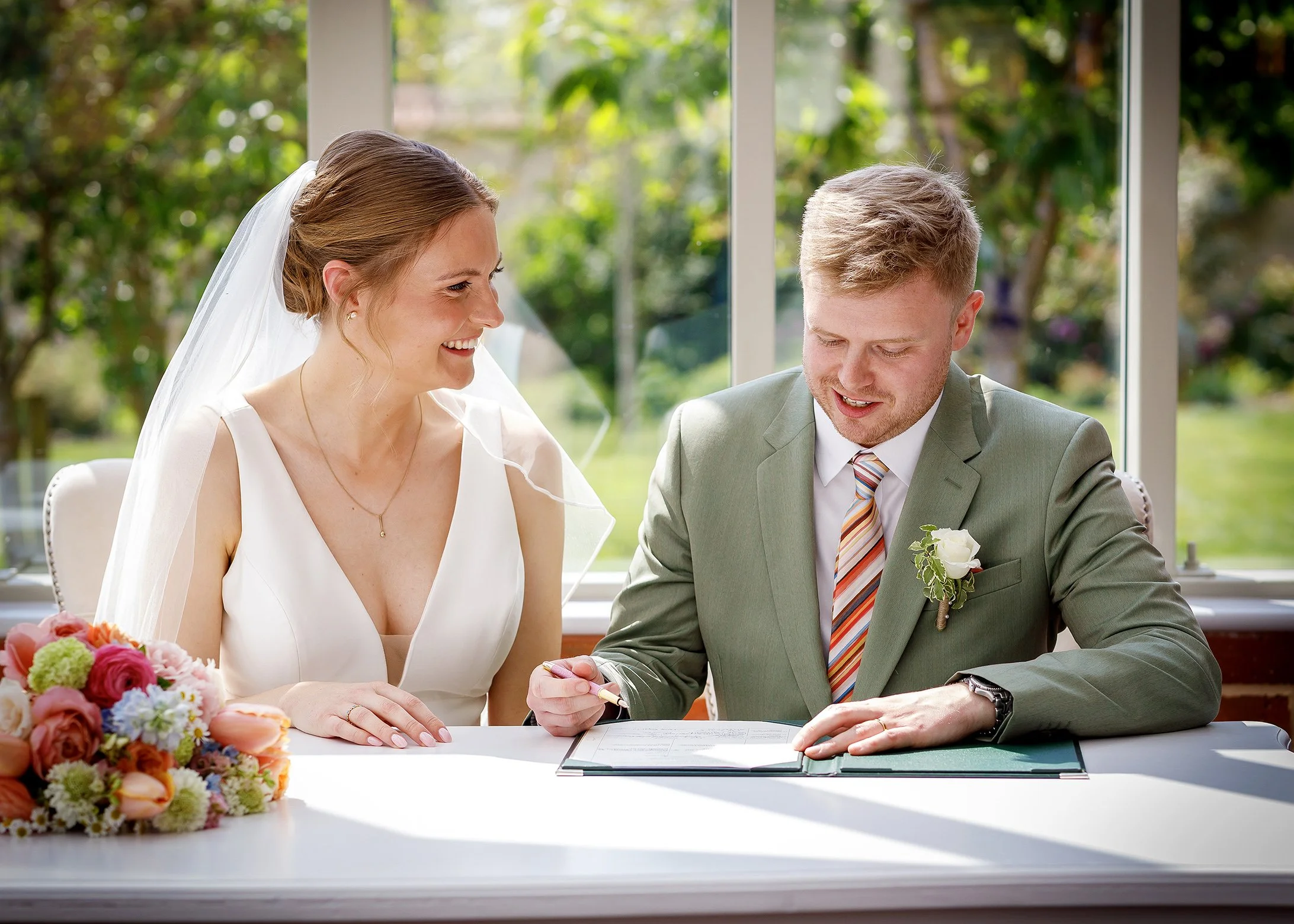 Bride and groom signing the register inside the Glasshouse at Syrencot in Wiltshire - Relaxed, Natural Wedding Photography