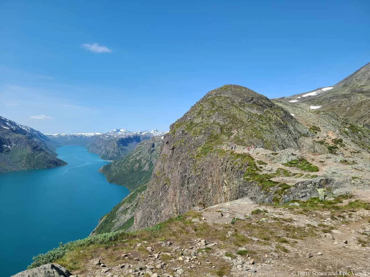 A herd path weaves along a cliff edge over a lake view on the Besseggen Ridge trail in Norway