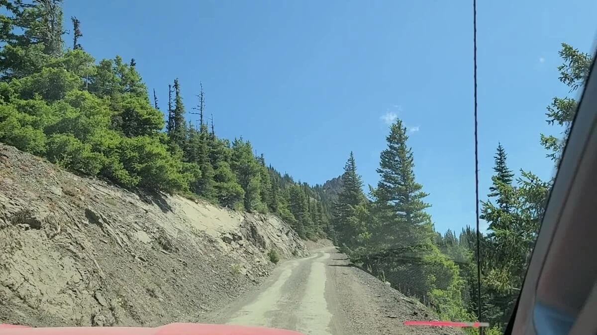 A narrow dirt road runs along a slope with exposure on the right