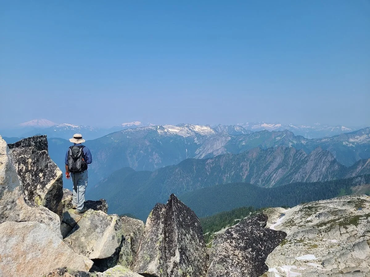 Hiker at the top of Hidden Lake Lookout enjoying the mountain views