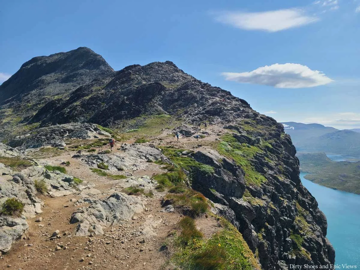 A herd path hugs a cliff edge along the Besseggen Ridge trail in Norway