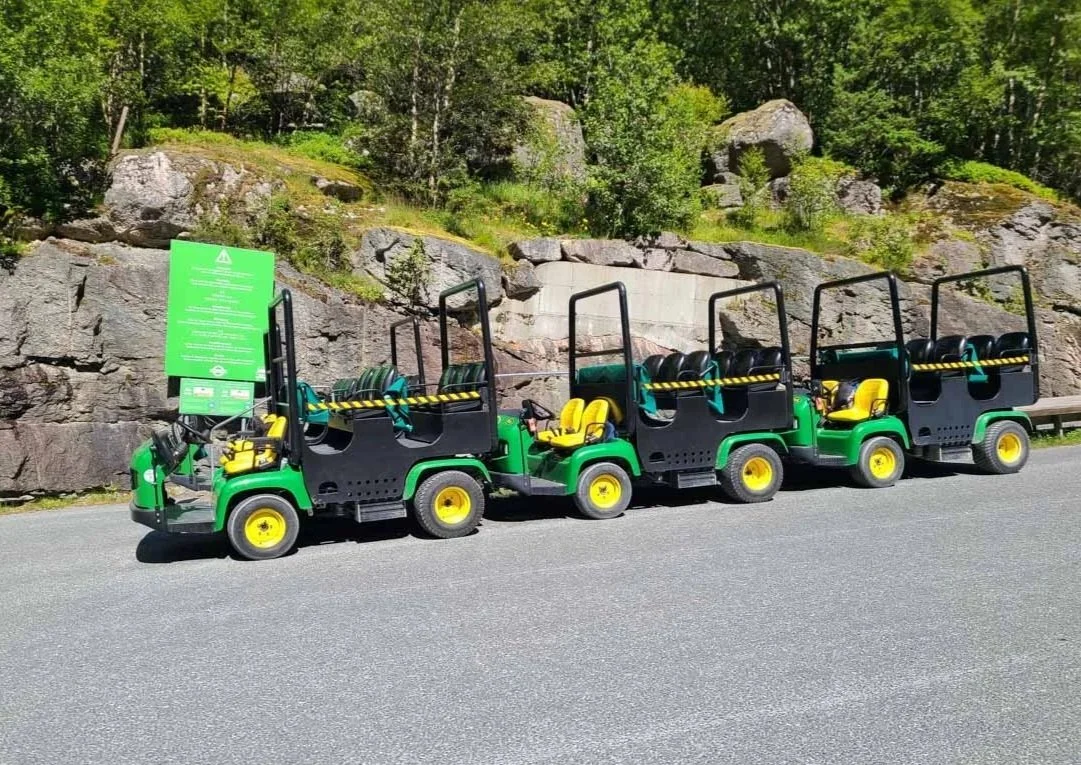 A series of troll cars sits in a parking lot at the start of the Briksdal Glacier trail