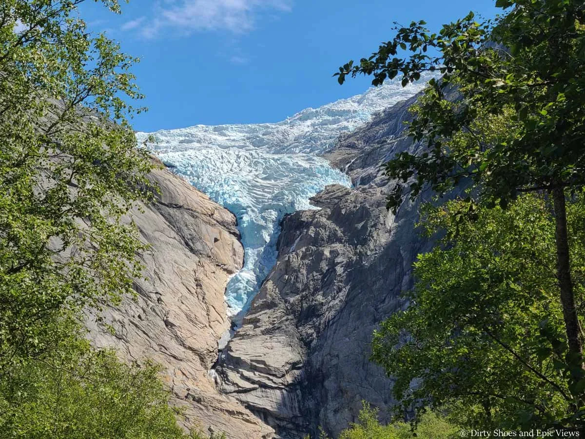 A white glacier cascades down a rocky cliff face along the Briksdal Glacier hike in Norway