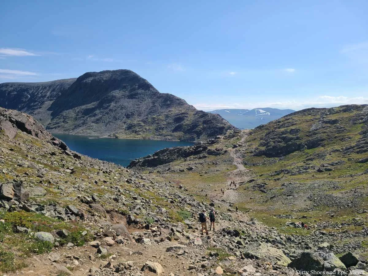 A herd path heads through a rocky valley towards a lake and narrow ridge on the Besseggen Ridge Trail in Norway