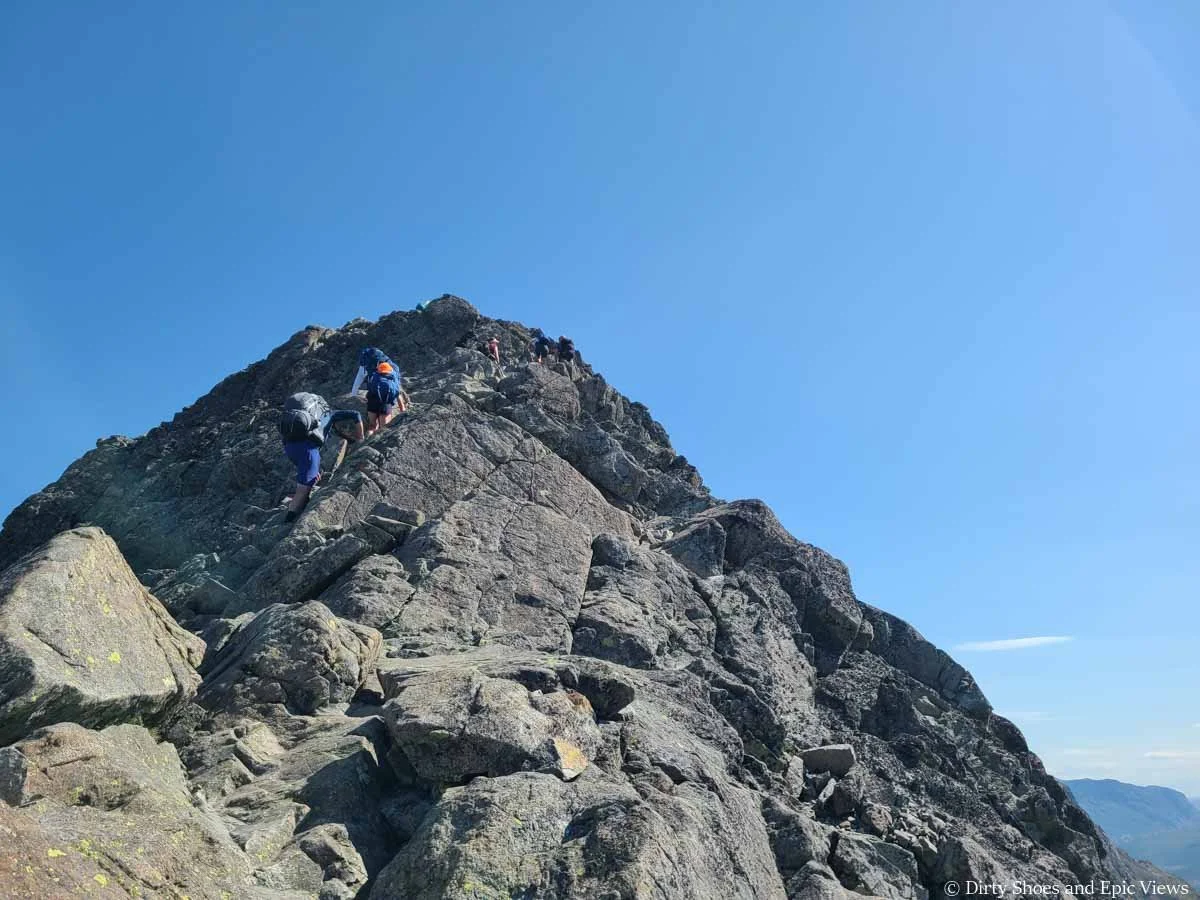 Hikers scramble up a narrow rocky ridge on the Besseggen Ridge hike in Norway