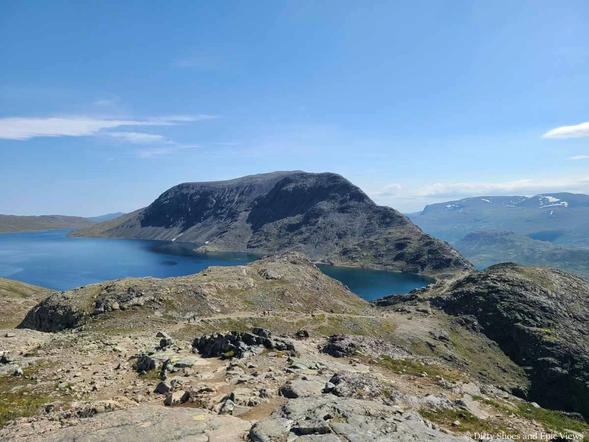 A herd path heads down a rocky slope towards mountain and lake views on the Besseggen Ridge trail