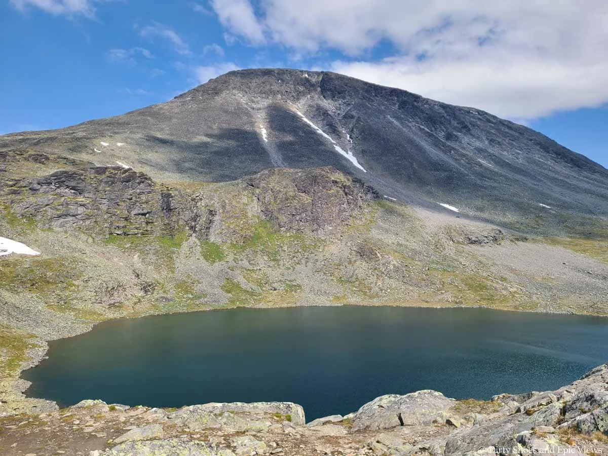 A mountain rises above a small blue lake on Besseggen Ridge