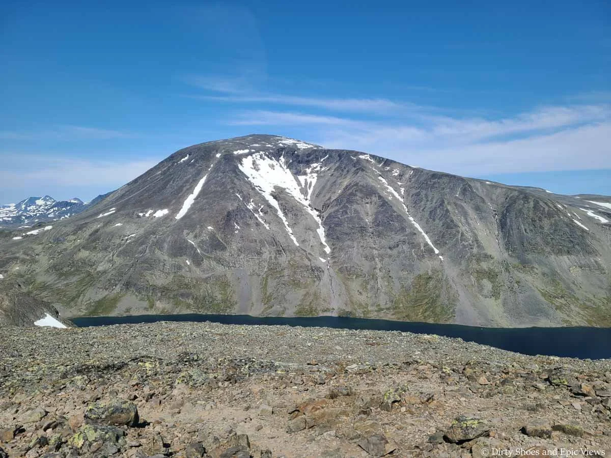 A mountain rises above a deep blue lake as seen from Besseggen Ridge in Norway