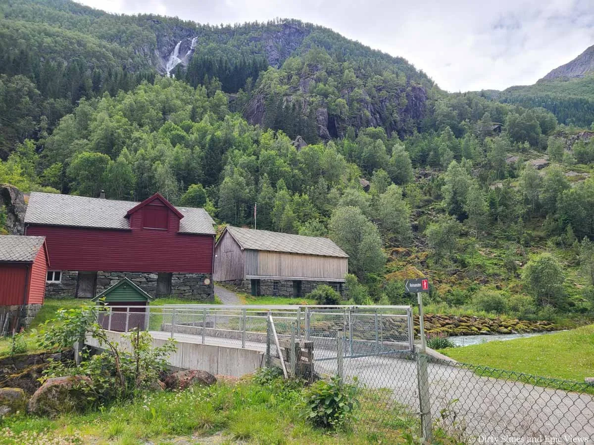 A bridge crosses a small stream towards a farm at the Reinanuten trailhead
