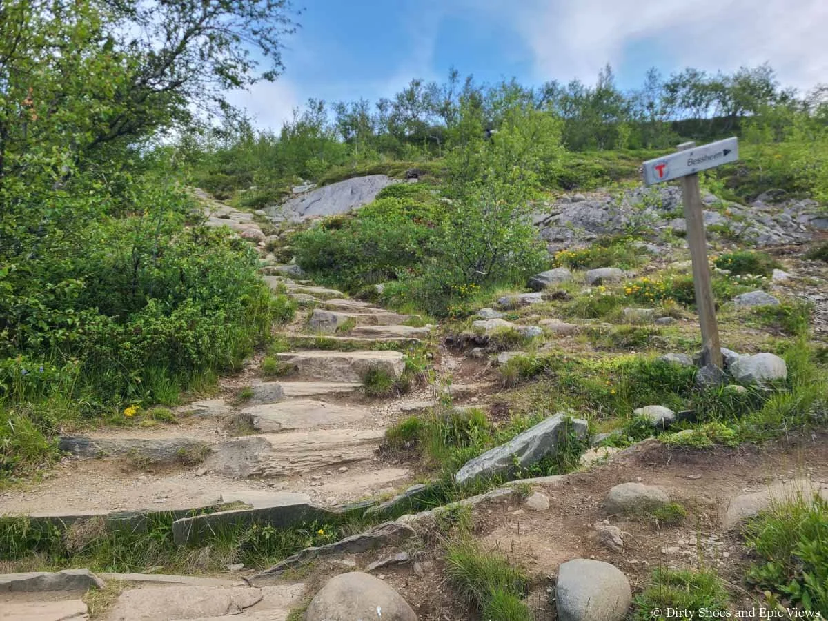Stone stairs climb up a grassy slope by a trail junction on the Besseggen Ridge hike in Norway