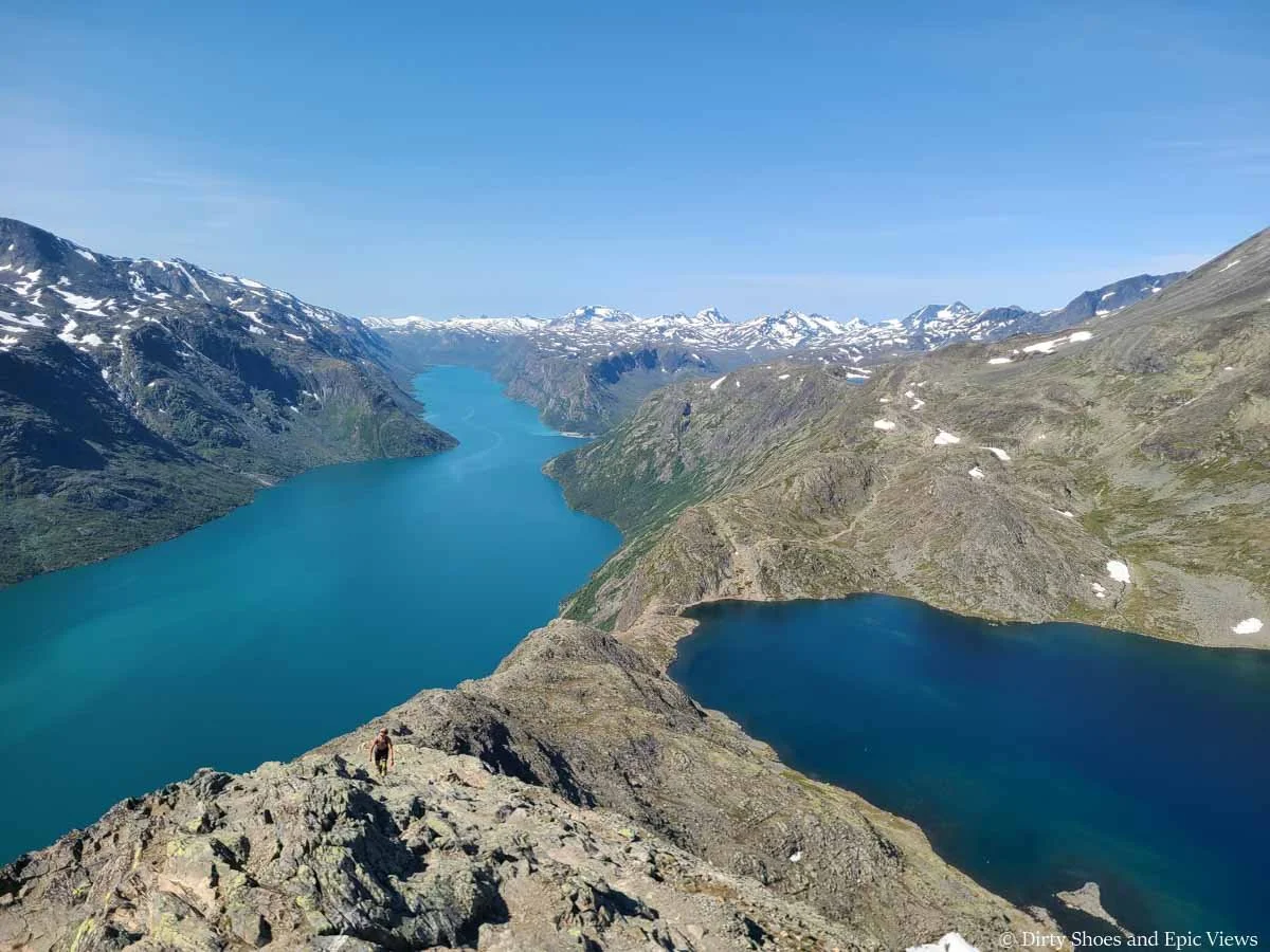 A narrow rocky ridge lies between two blue lakes along the Besseggen Ridge trail in Norway