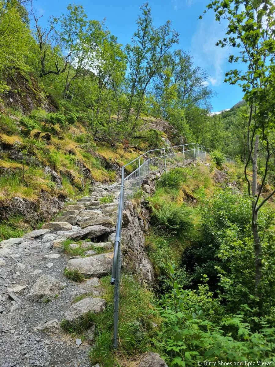 A rocky fenced path ascends a grassy hillside on the way to Briksdalsbreen in Norway