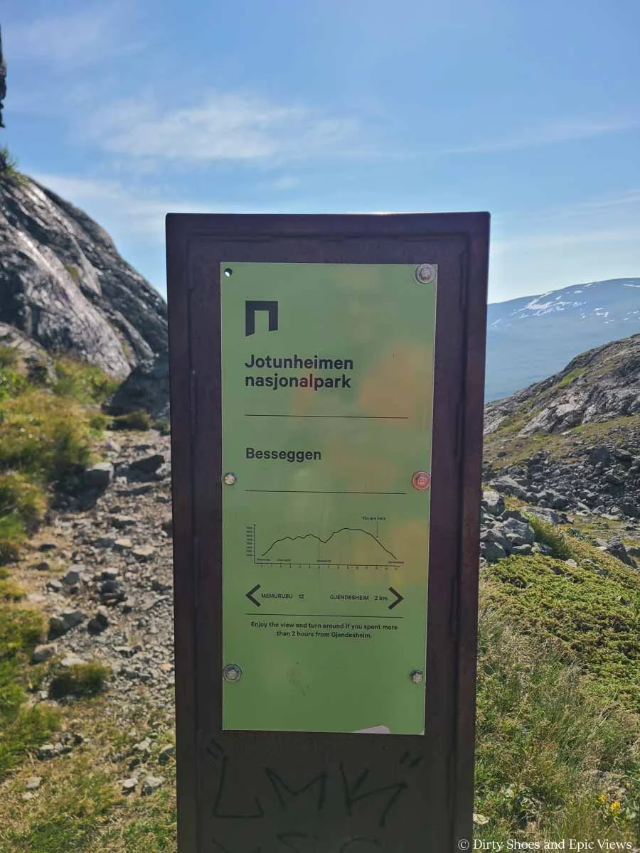 A sign on the Besseggen Ridge trail marks the location and distance from the trailhead