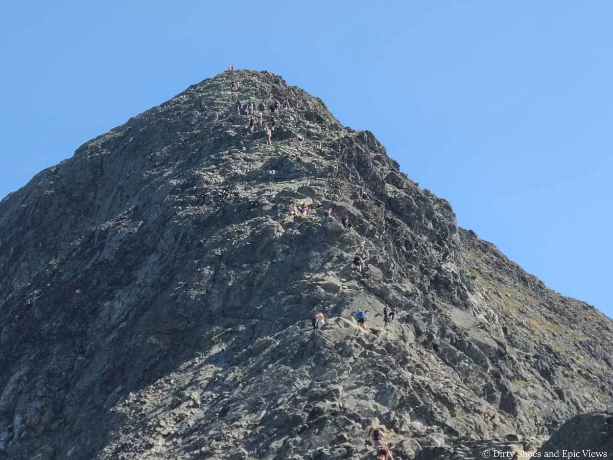 A line of hikers scramble up a narrow rocky spine on the Besseggen Ridge hike in Norway