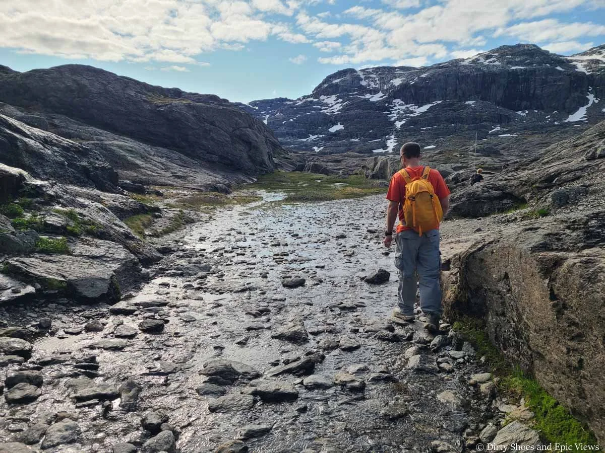 A hiker navigates a small stream along the Trolltunga hike