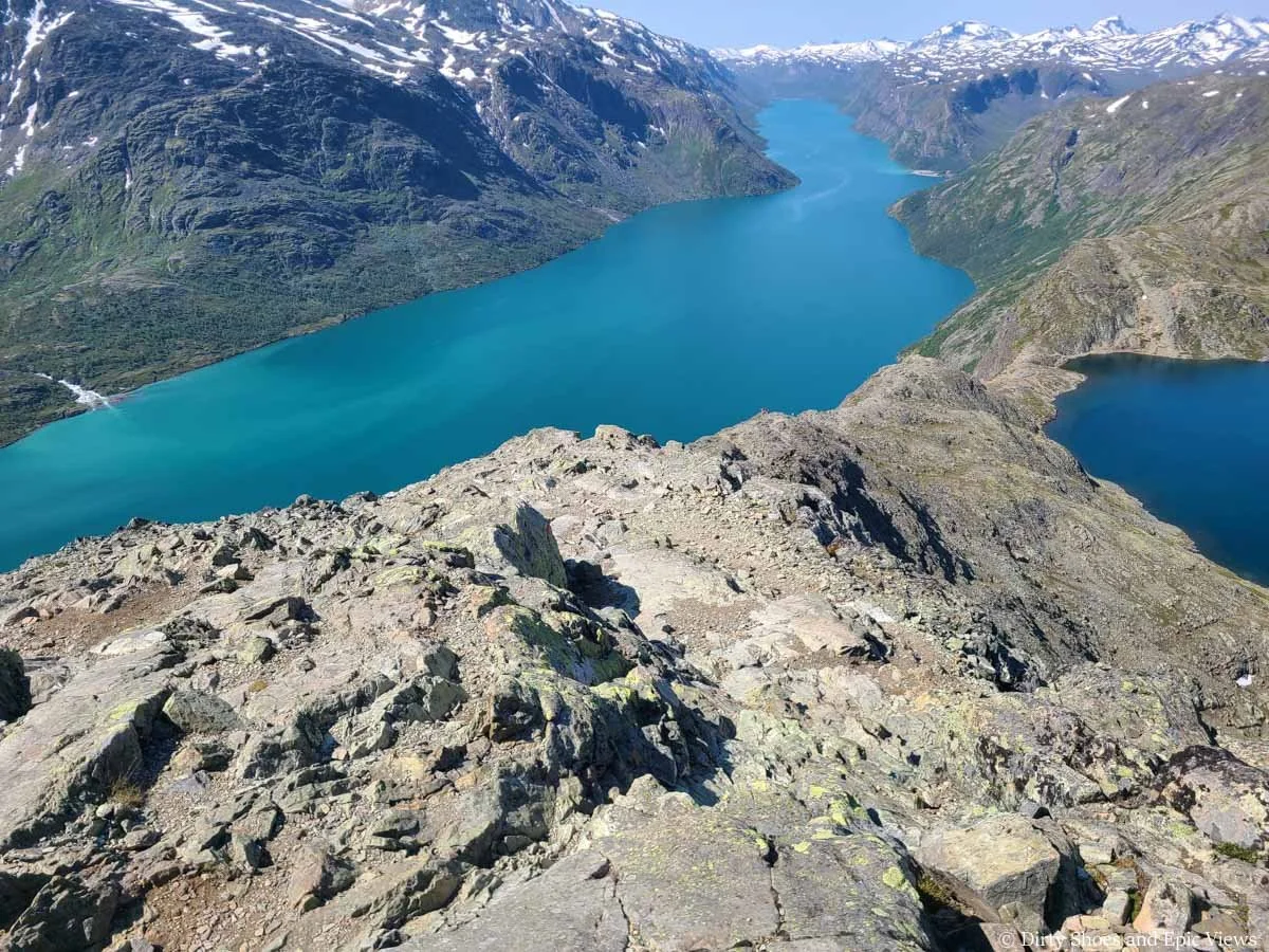 A herd path descends a narrow rocky spine above two lakes on the Besseggen Ridge hike