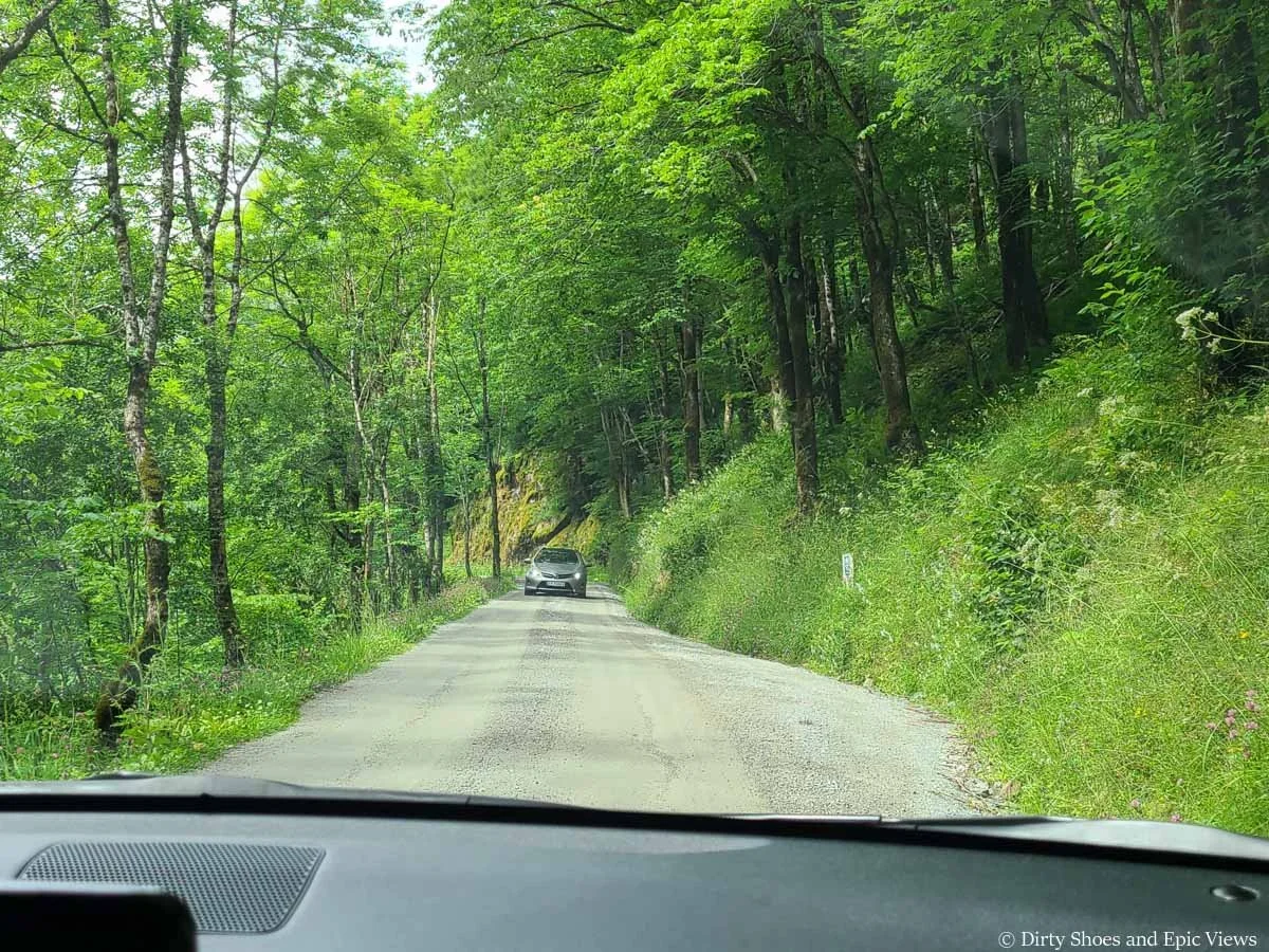 An oncoming car drives down a narrow gravel road towards the camera along the road to the Reinanuten trailhead in Norway