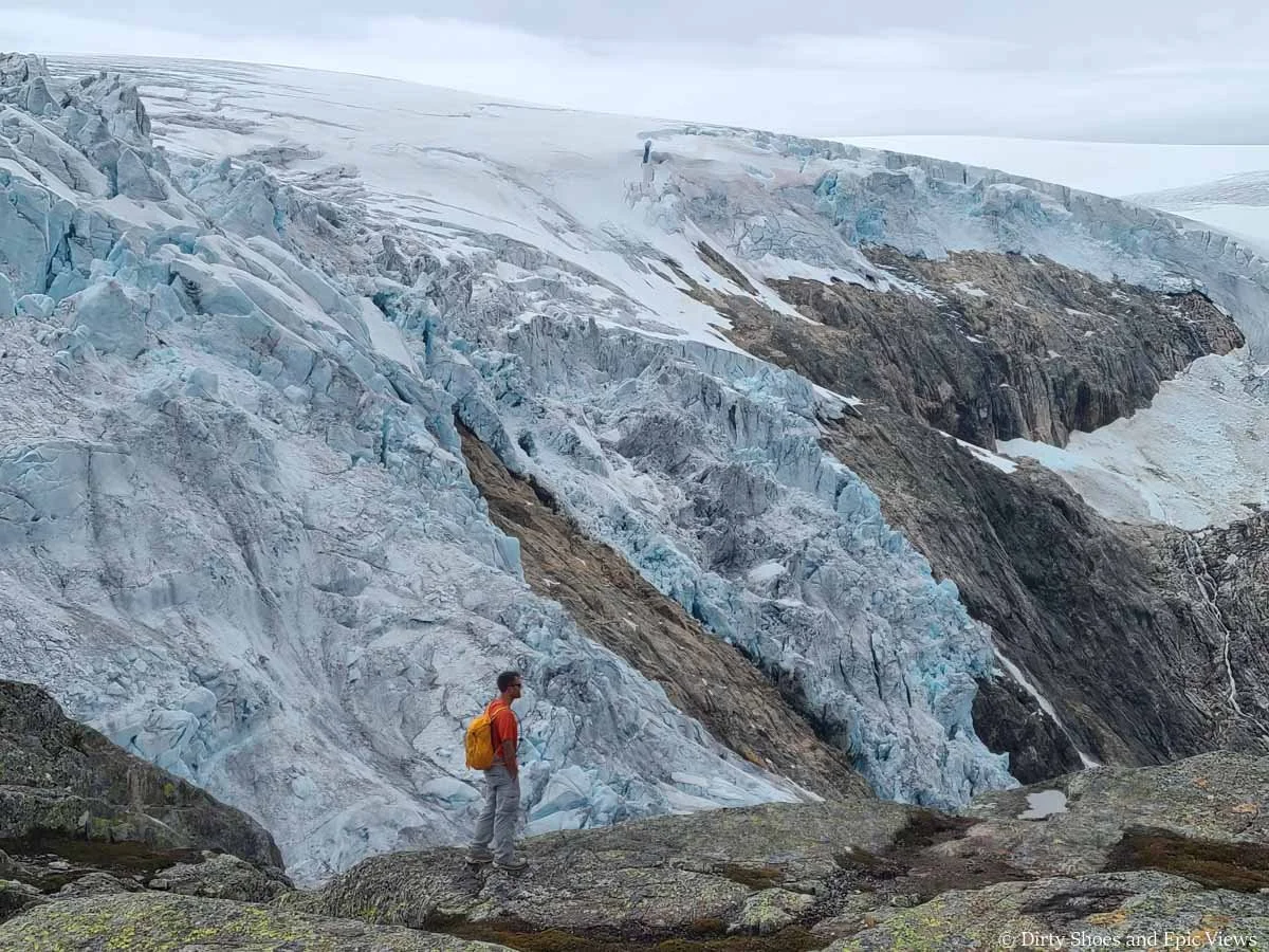 A hiker stands in front of a view of a massive glacier on the Reinanuten hike in Norway