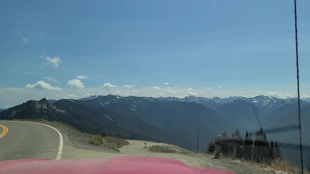 The entrance to Obstruction Point Road marked by a sign and a dirt road that dips down off the main road