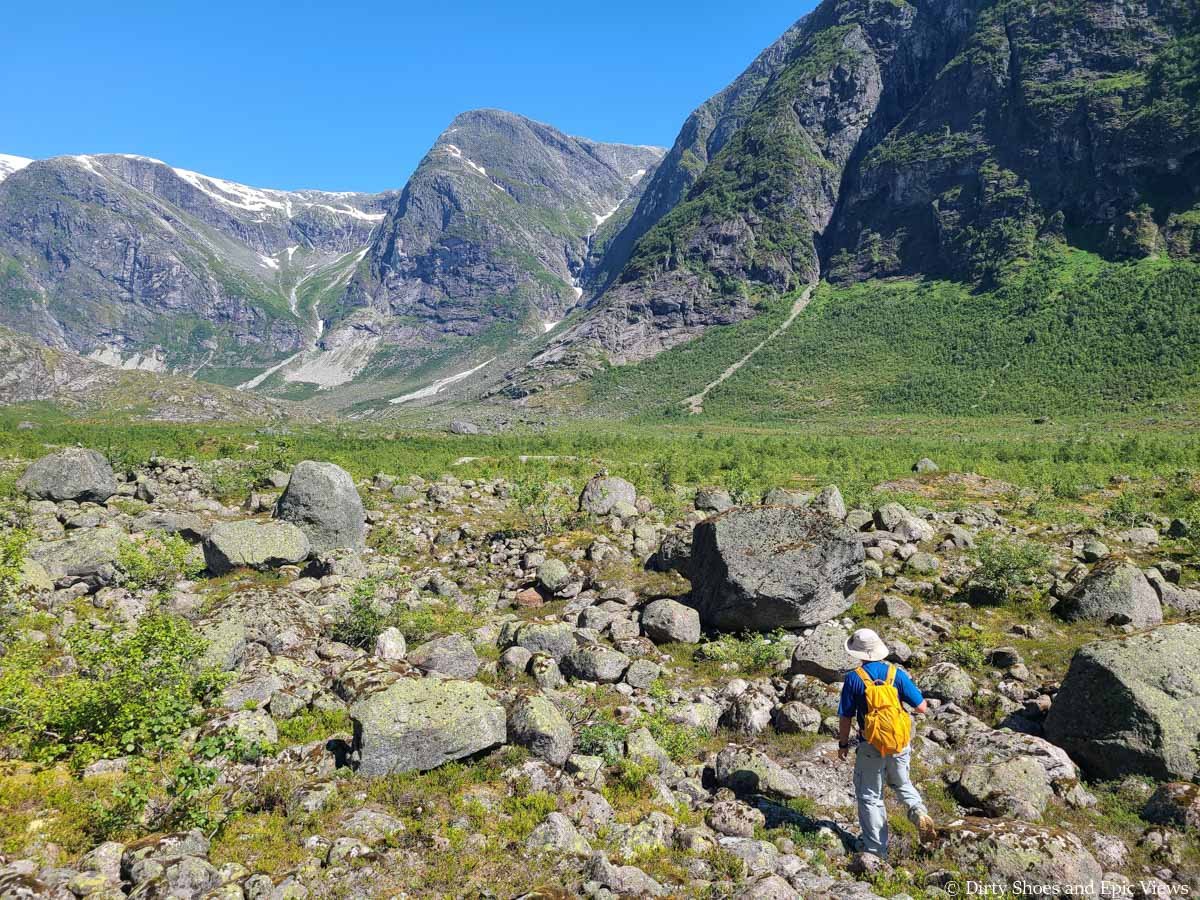A hiker navigates a rocky landscape towards mountain views on the Austerdalsbreen hike in Norway