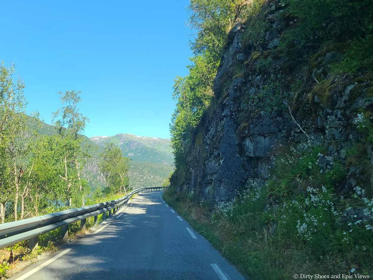 A narrow road runs along a rock wall and turns into a blind turn on the road to Austerdalsbreen in Norway