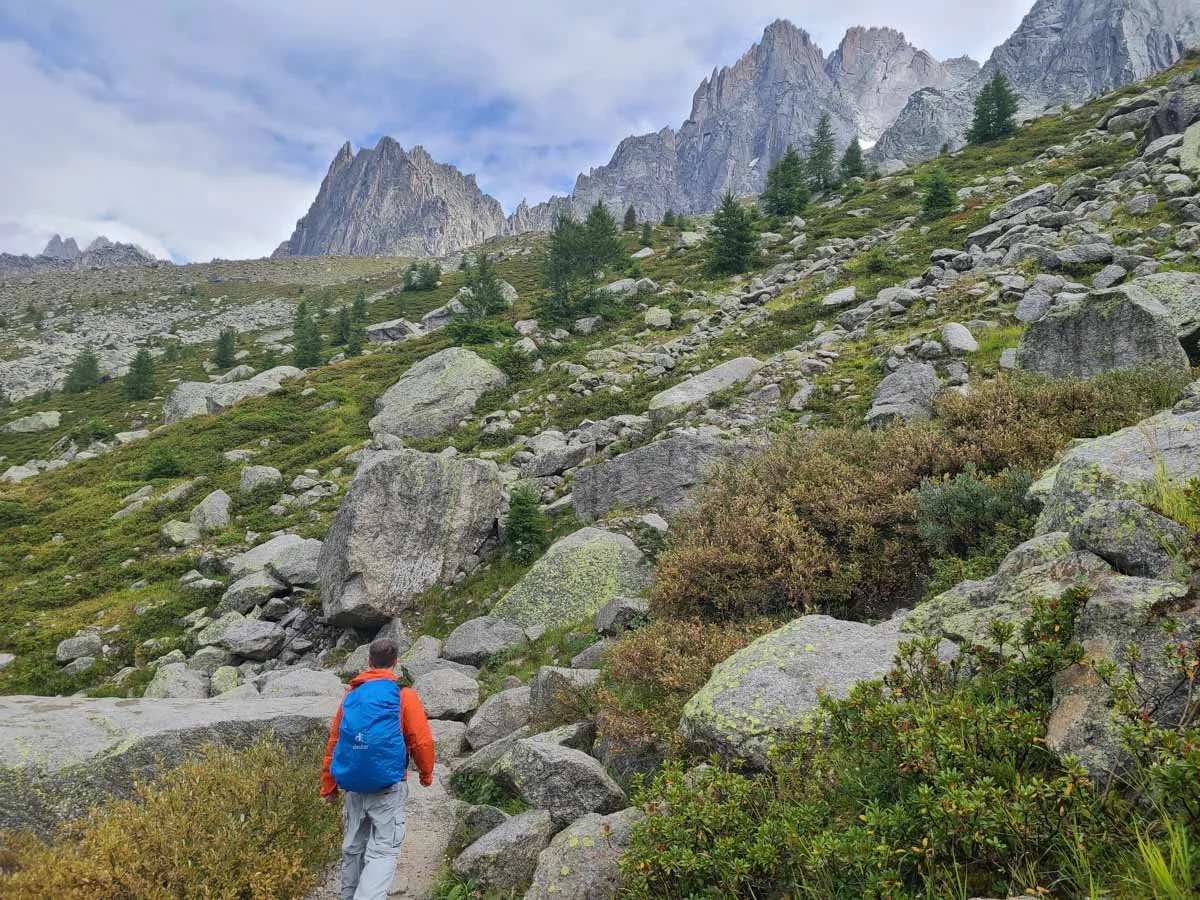 A hiker along the Grand Balcon Nord in Chamonix with views of jagged mountains and green meadows