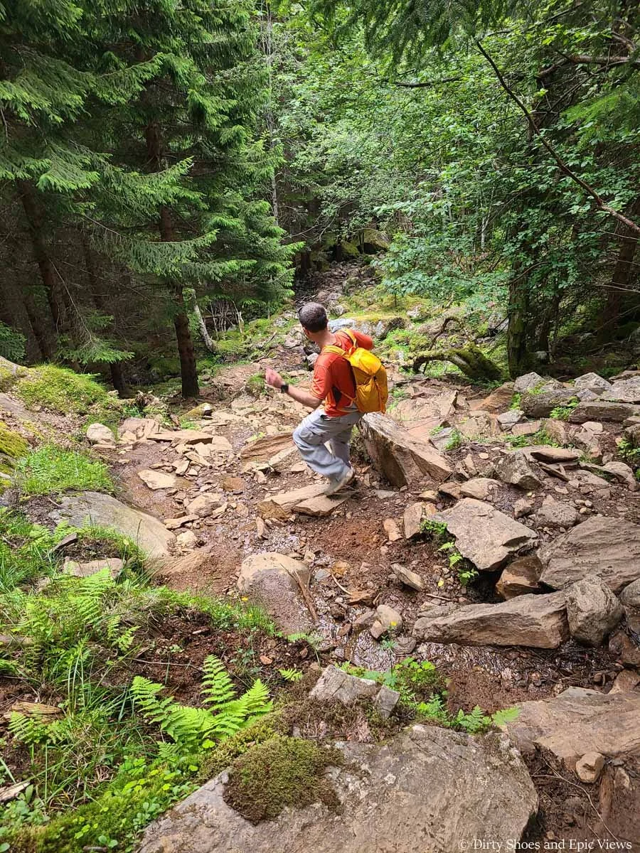 A hiker descends a rocky rugged trail on Reinanuten in Norway
