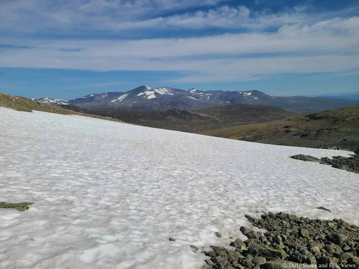 A snow patch sits in front of mountain views along the Besseggen Ridge hike in Norway