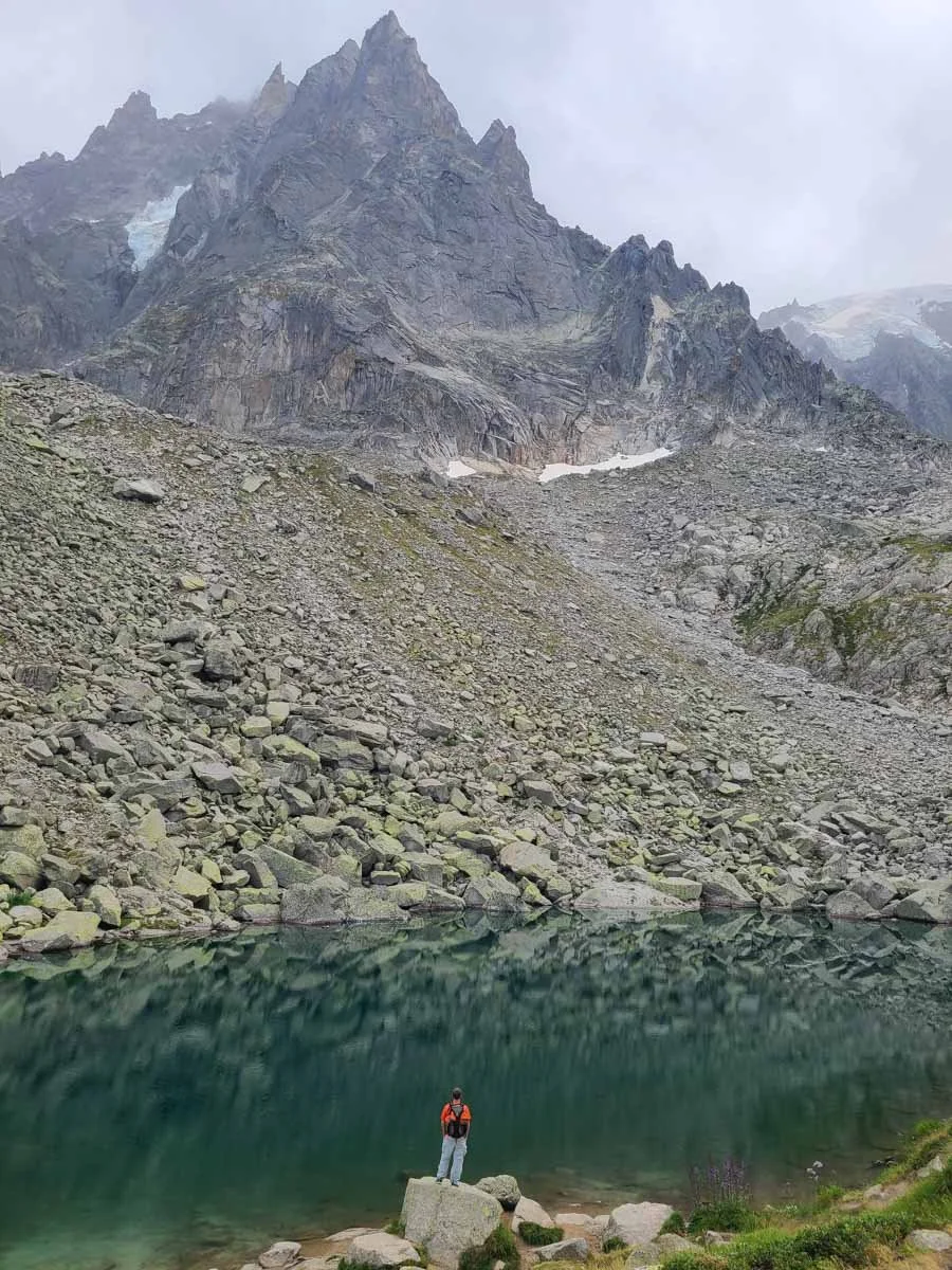 A hiker stands on a rock at the edge of Lac Bleu in Chamonix
