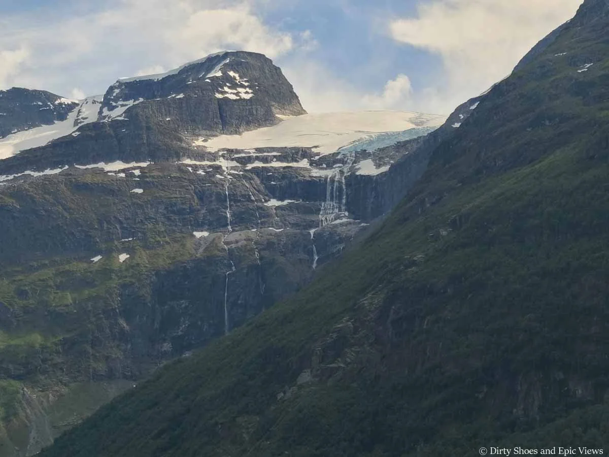 Waterfalls run from a glacier down cliff faces in Norway
